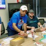 Volunteers from Cox Communications help each other assemble STEM for All Kits. (Photography by Katherine Nicole)