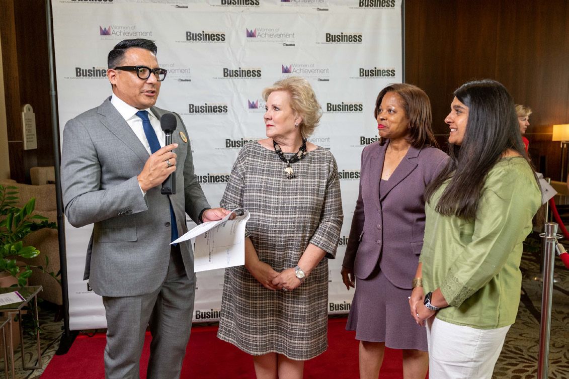 An emcee interviews three past storytellers on the media backdrop before the ceremony.