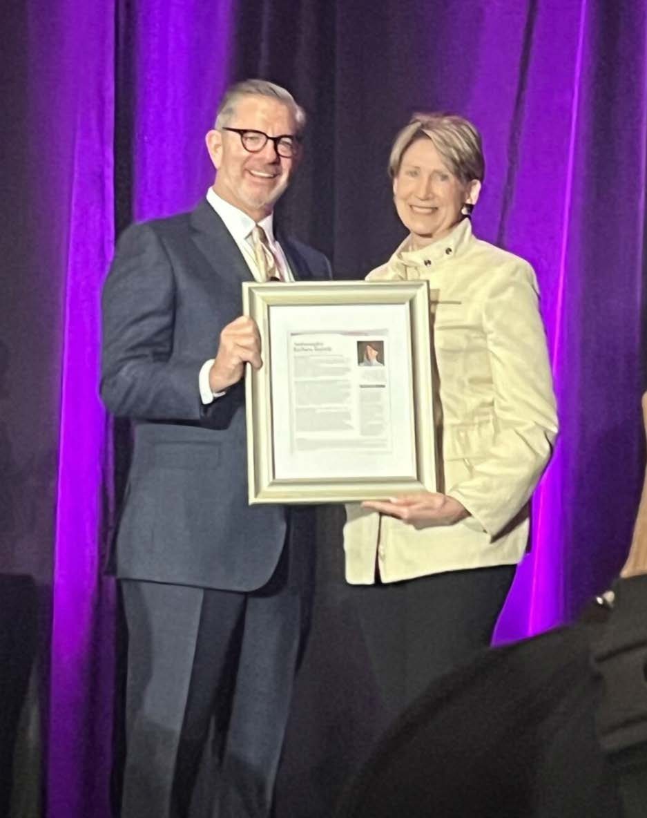 The 2024 Lifetime Honoree receives her framed certificate on stage.