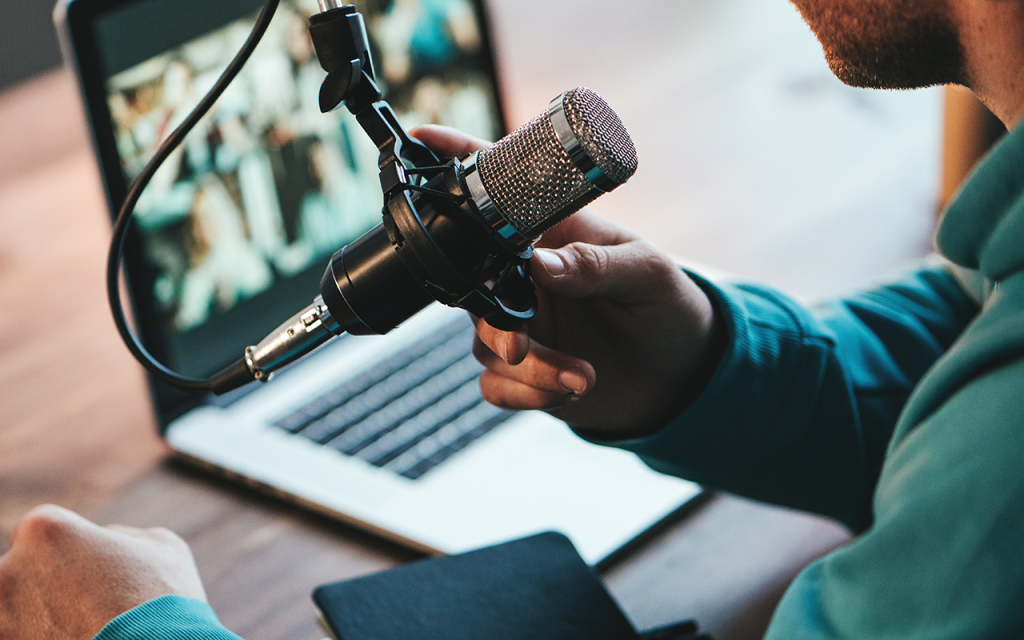 Podcaster speaking into a microphone in front of a laptop