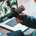 Podcaster speaking into a microphone in front of a laptop