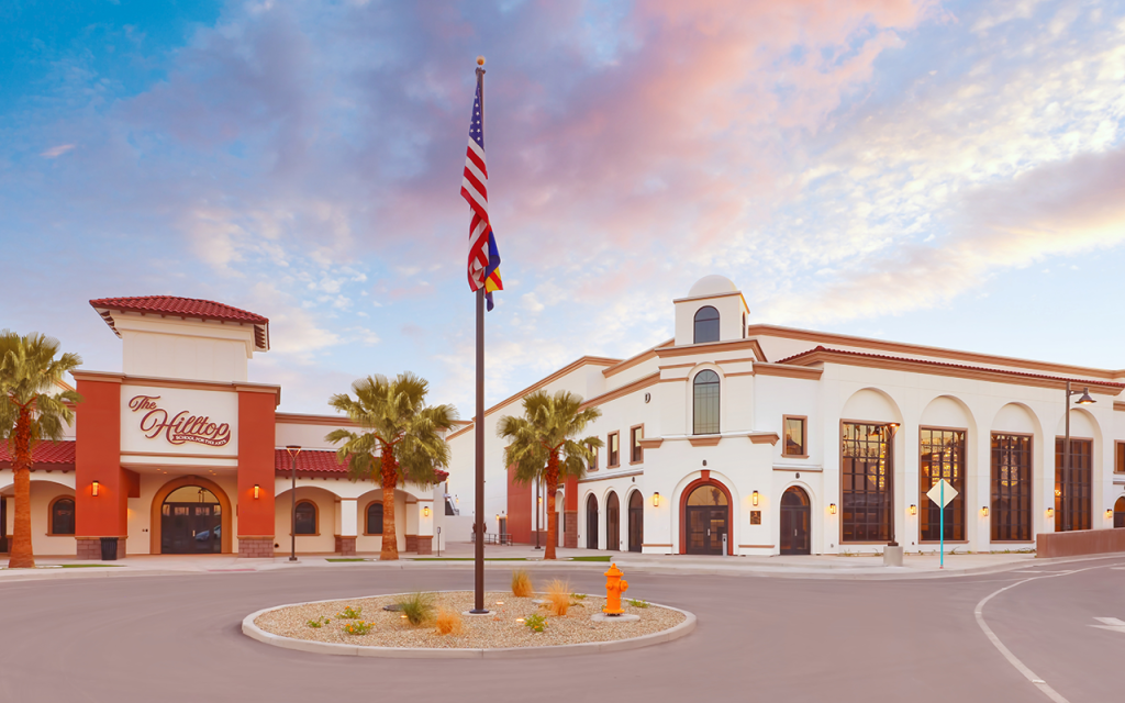 Exterior of the Hilltop Theatre and Concert Hall at dusk with an American flag