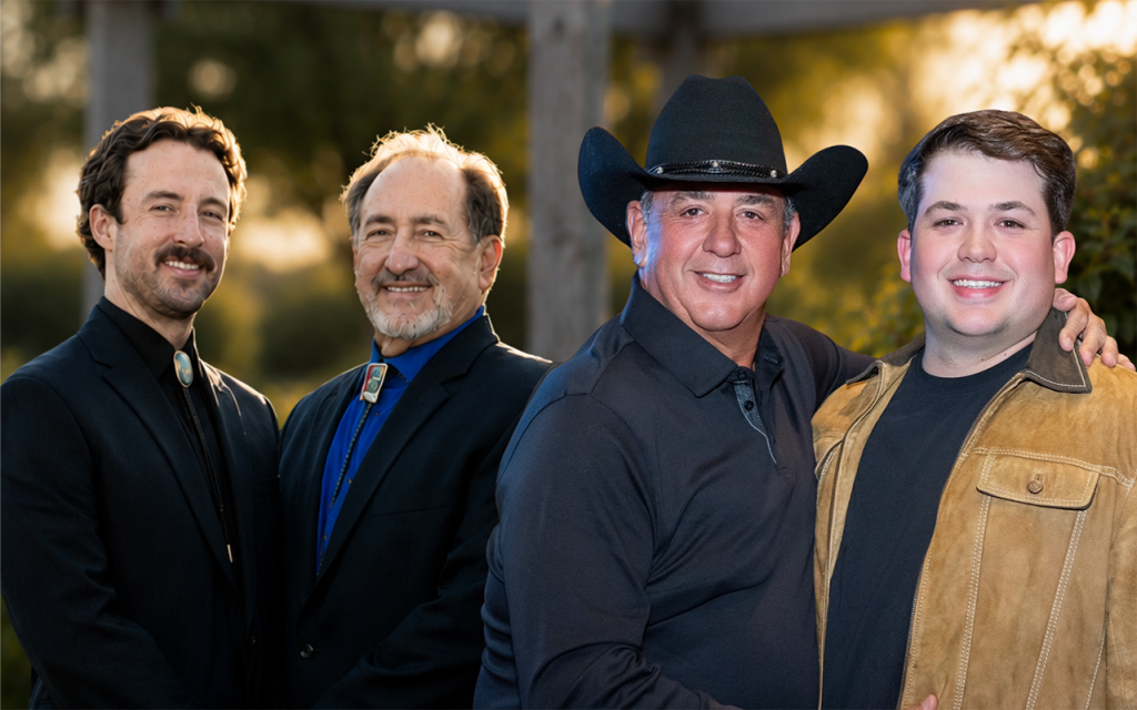 Group portrait of four men in business attire, one wearing a cowboy hat