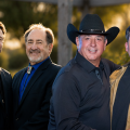 Group portrait of four men in business attire, one wearing a cowboy hat