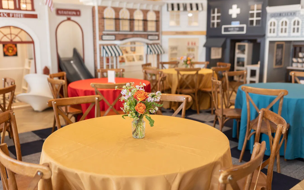 Dining table set in front of a miniature village of storefronts at The Little Play Avenue