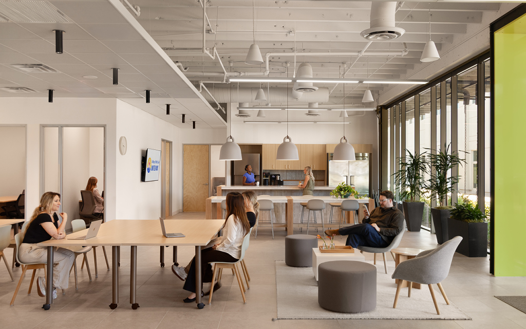Open workspace with shared tables, lounge seating and a kitchen island in a bright office