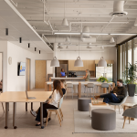 Open workspace with shared tables, lounge seating and a kitchen island in a bright office
